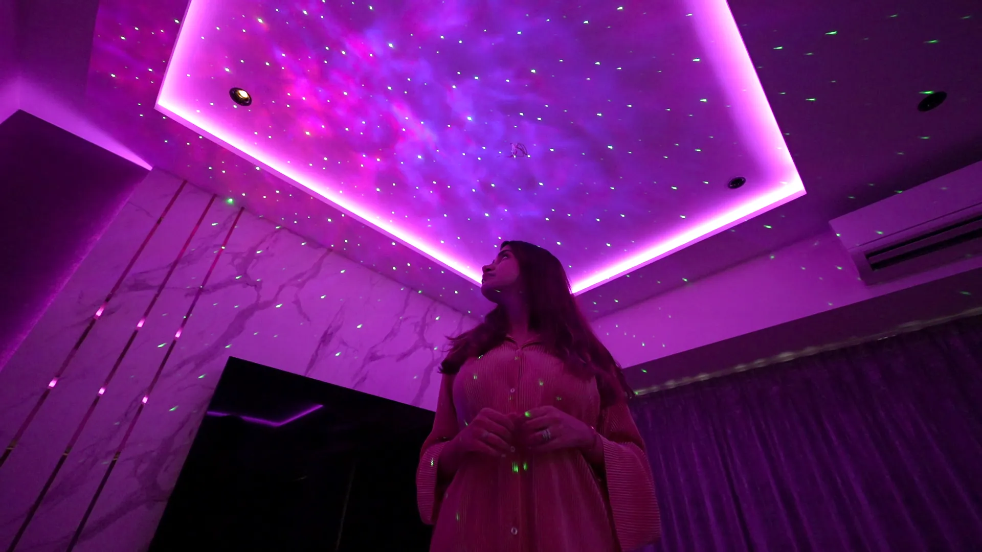 A living room ceiling washed in deep magenta light with a starlight field above
